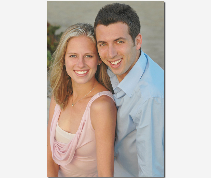 couple in pink and blue sitting on a beach
