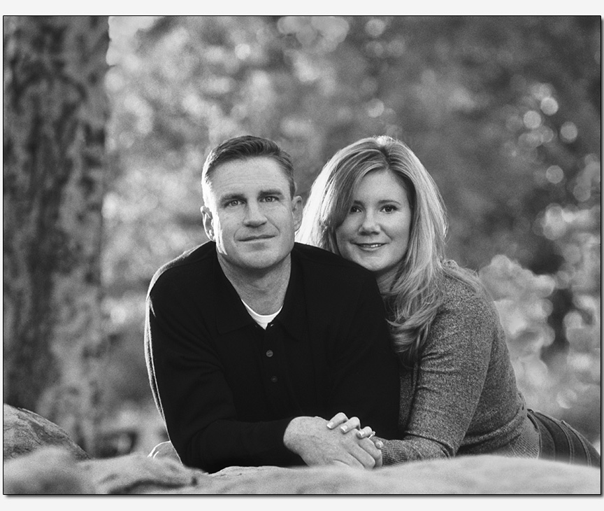 on-location couple laying on boulder forested park